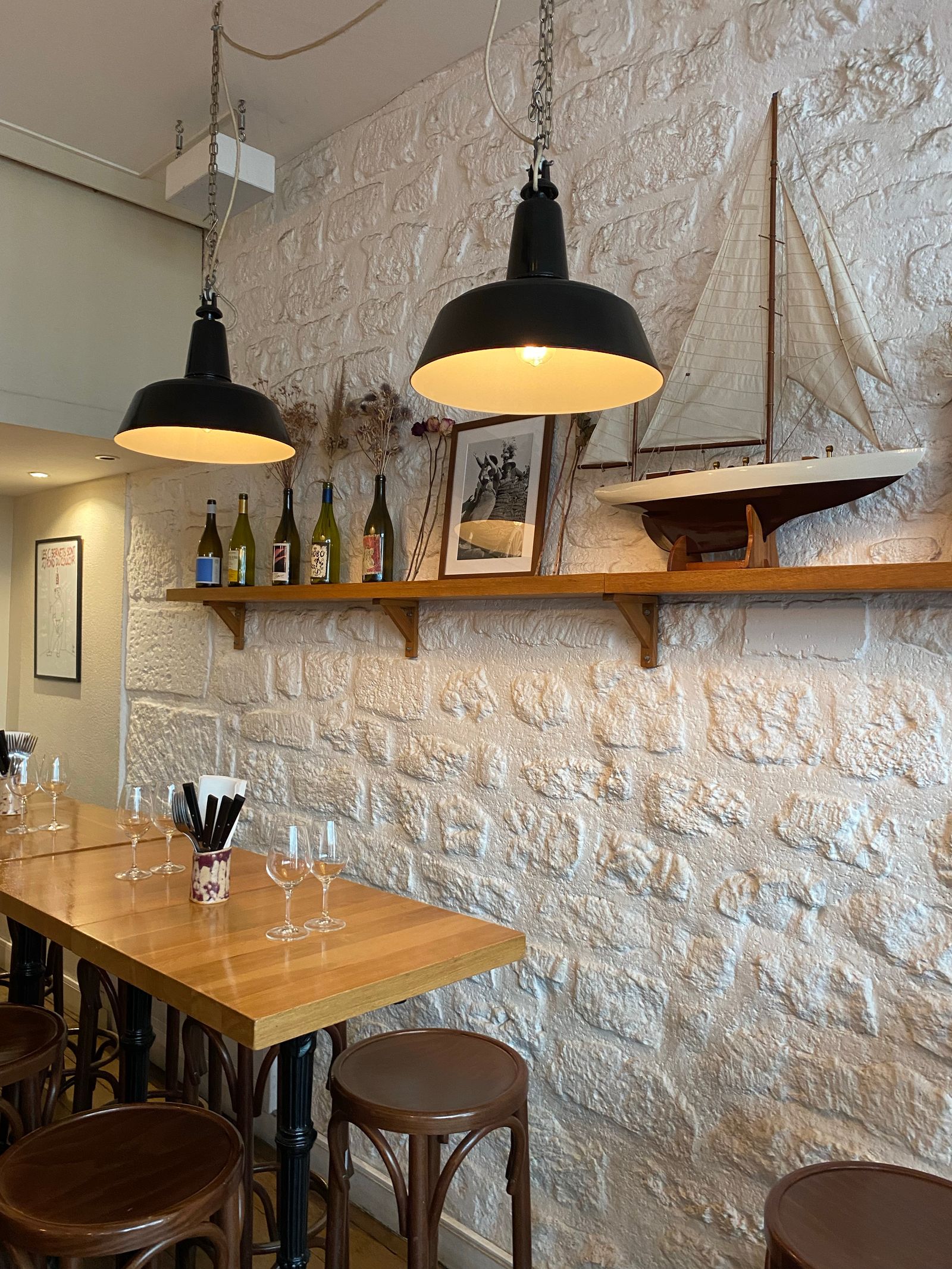 A bistro with warm pendant lights, wooden tables and a model sailing boat