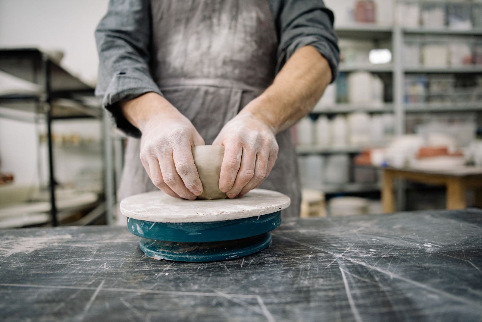 A potter forming a vessel on a wheel in a ceramics studio